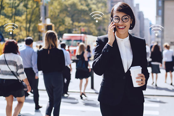 A woman talking over the phone walking on the street connected to Wi-Fi