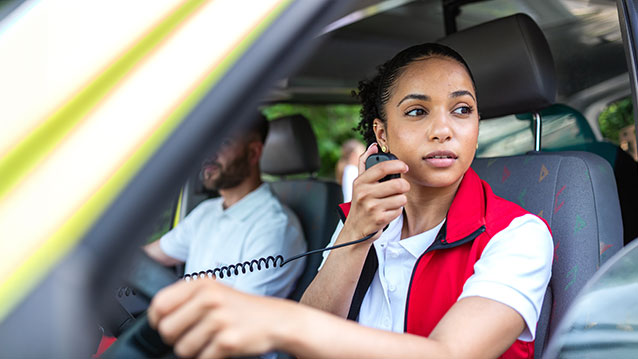 First responder using a reliable communication device in a vehicle, demonstrating Bell's critical infrastructure for public safety.