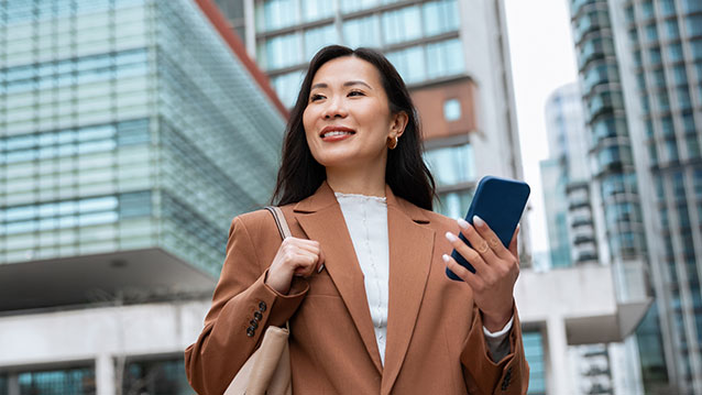 Professional woman smiling while using her smartphone, highlighting Bell's flexible business mobility rate plans for teams.