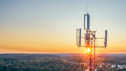 A cellular tower at sunset overlooking a wide landscape, representing secure, reliable mobility and vast 5G coverage that helps government staff stay connected, productive and protected with Bell.