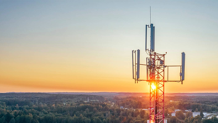 A high-angle view of a telecommunications tower at sunset, representing Bell's custom-designed connectivity systems built for unique and complex environments.
