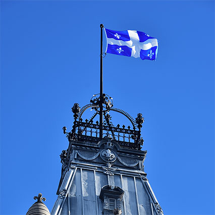 A Québec flag atop a provincial parliament building against a clear blue sky, symbolizing scalable, secure connectivity and digital solutions that support essential provincial services.
