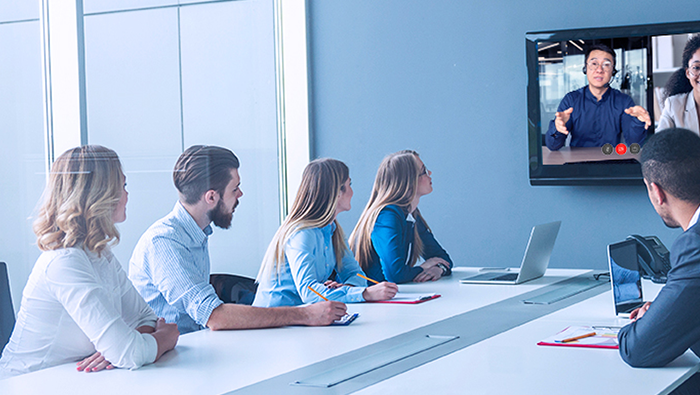 Colleagues in an office maintaining productivity by connecting with remote workers on a video call using a voice and collaboration solution from Bell.